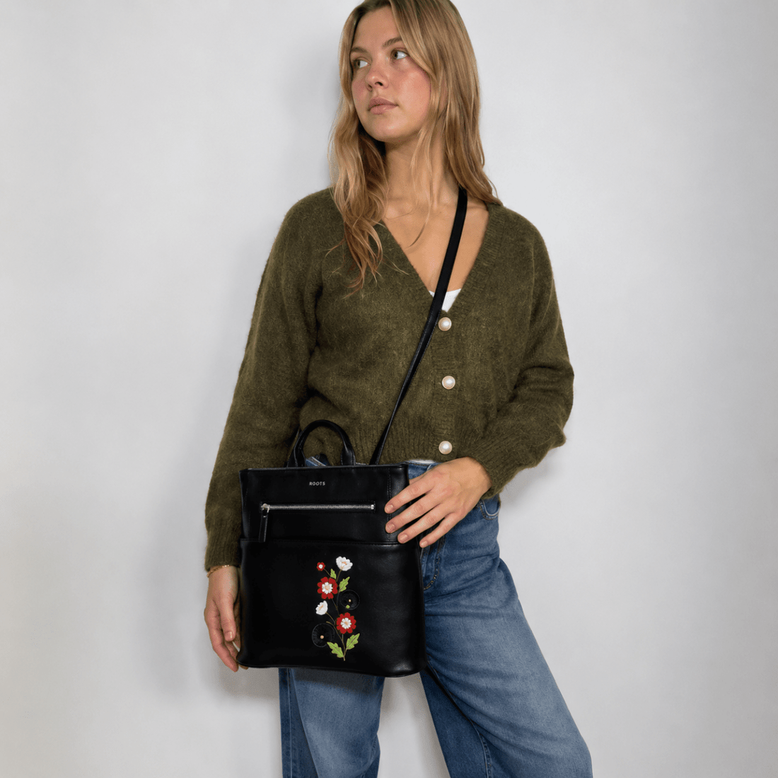 Woman holding a black handbag with floral embroidery against a plain background - okotoks hc pharmacy