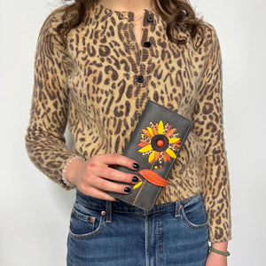 Person wearing a leopard print shirt holding a grey wallet with floral designs. - okotoks hc pharmacy