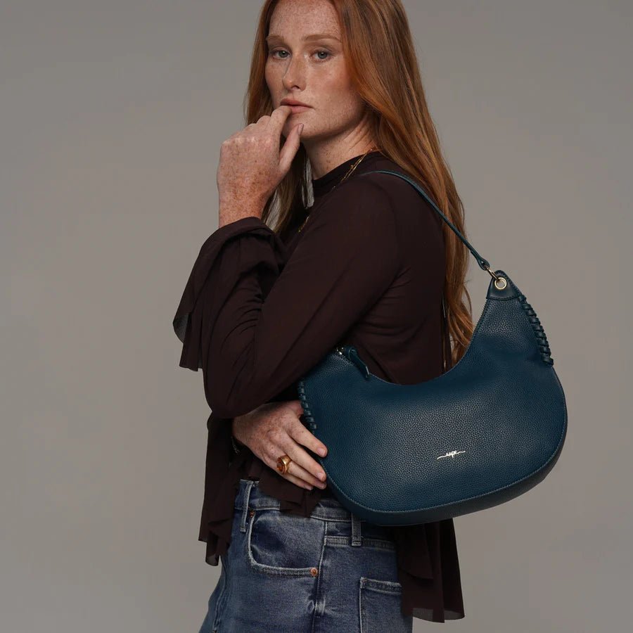 Woman holding a blue handbag against a plain background - okotoks hc pharmacy