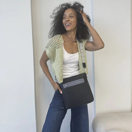 Woman holding a black bag against a neutral background - okotoks hc pharmacy
