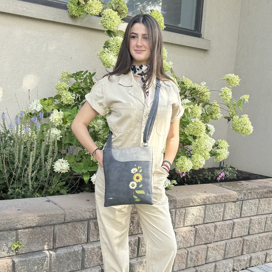 Woman standing outdoors with a floral-patterned bag, surrounded by greenery. - okotoks hc pharmacy