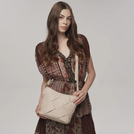 Woman holding a beige handbag against a plain background - okotoks hc pharmacy