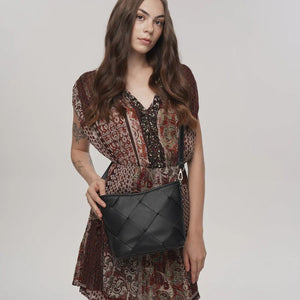 Woman holding a black quilted handbag against a plain background - okotoks hc pharmacy