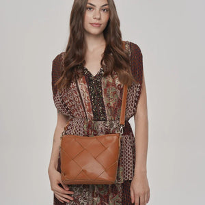 Woman holding a brown woven handbag against a plain background - okotoks hc pharmacy