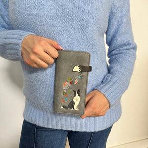 Person holding a gray wallet with a dog design, wearing a blue sweater. - okotoks hc pharmacy