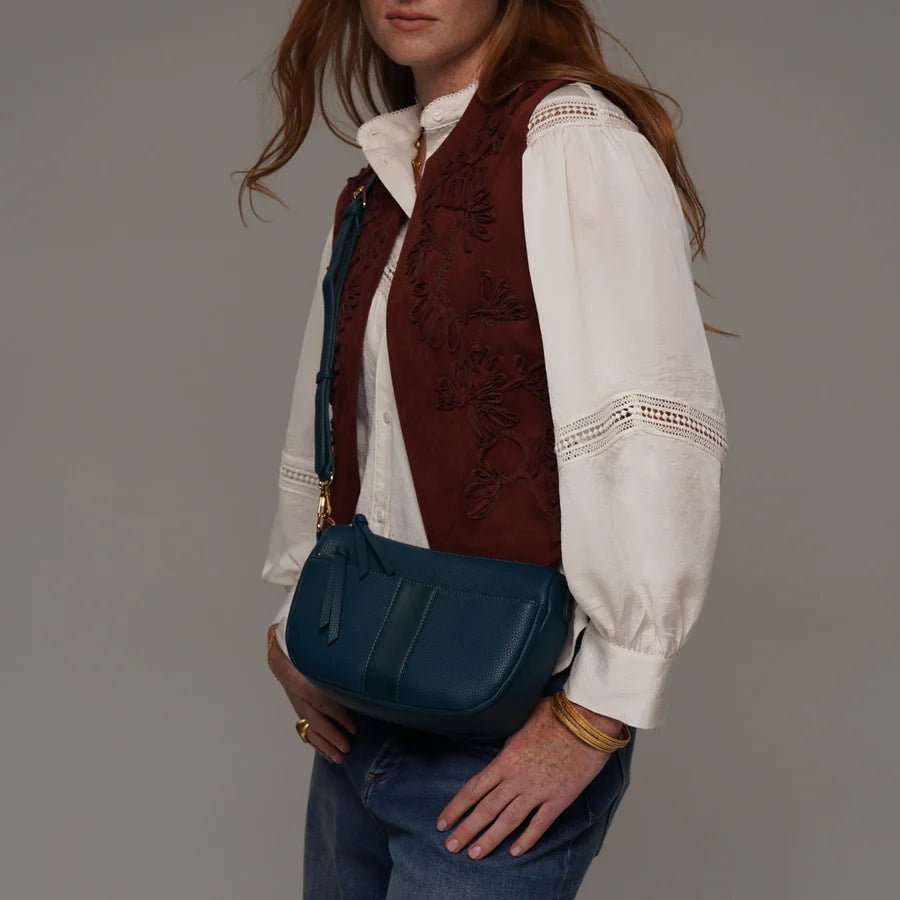 Woman holding a blue handbag against a neutral background - okotoks hc pharmacy