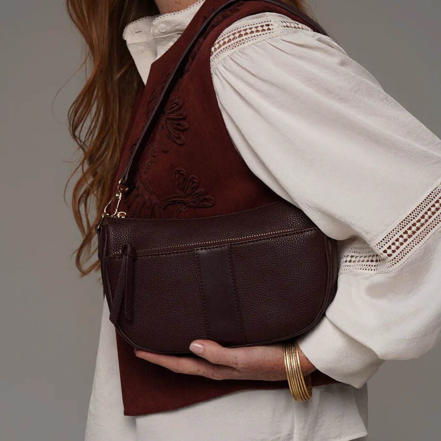 Person wearing a wine coloured bag with a plain background - okotoks hc pharmacy