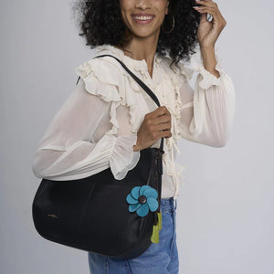 Woman holding a black bag with a blue flower detail against a gray background - okotoks hc pharmacy