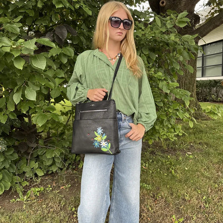 Person holding a black handbag with floral design outdoors - okotoks hc pharmacy
