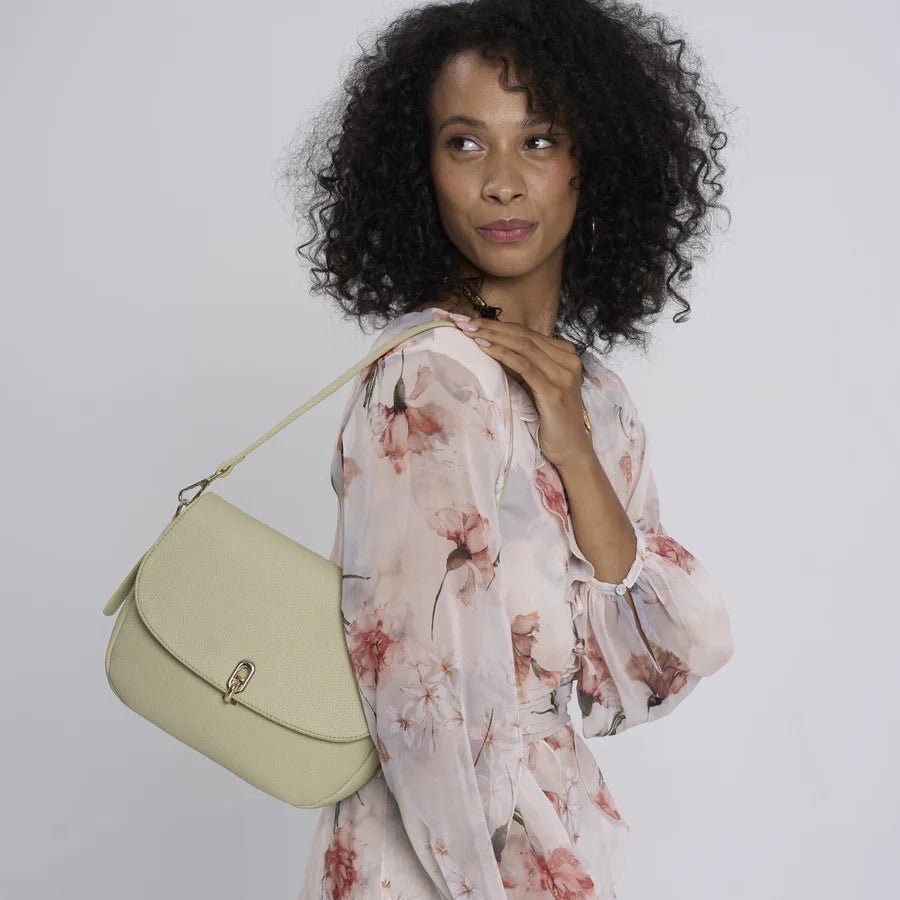 Woman holding a sage handbag against a plain background - okotoks hc pharmacy