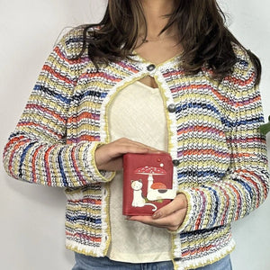Person wearing a colorful striped jacket holding a red wallet with a cat design. - okotoks hc pharmacy