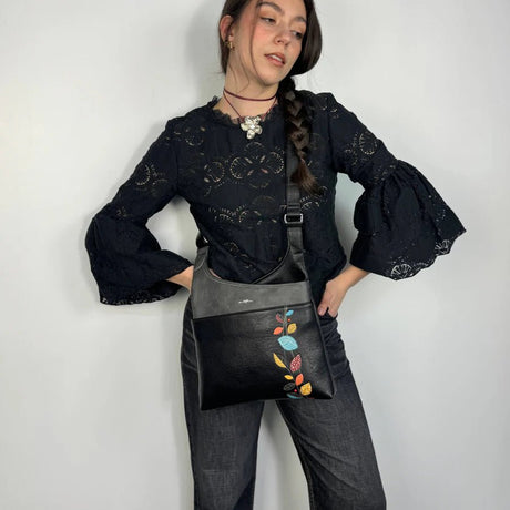 Woman holding a black bag with colorful floral embroidery against a white background - okotoks hc pharmacy