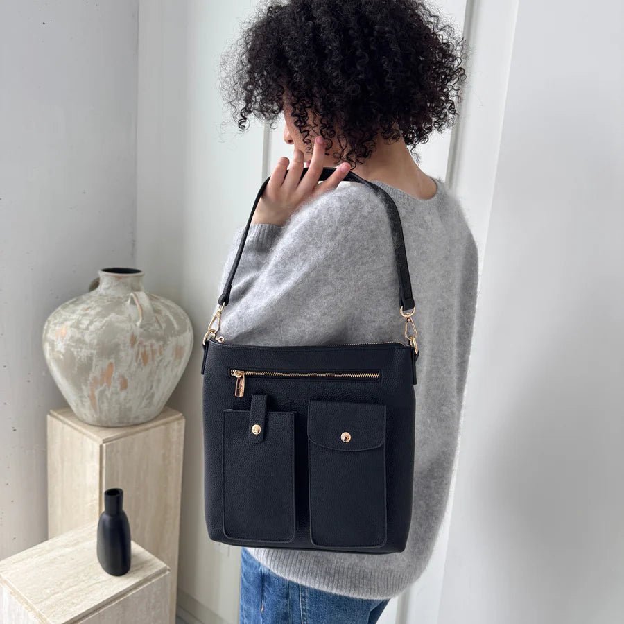 Person holding a black handbag in a minimalistic indoor setting - okotoks hc pharmacy