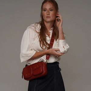 Woman holding a red handbag against a plain background - okotoks hc pharmacy