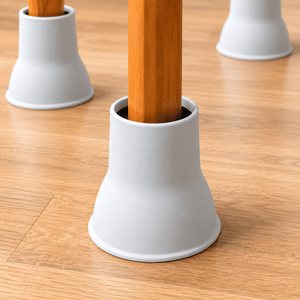 White bell-shaped table leg protectors on a light wood floor, with wooden table legs inserted in the center. - okotoks hc pharmacy
