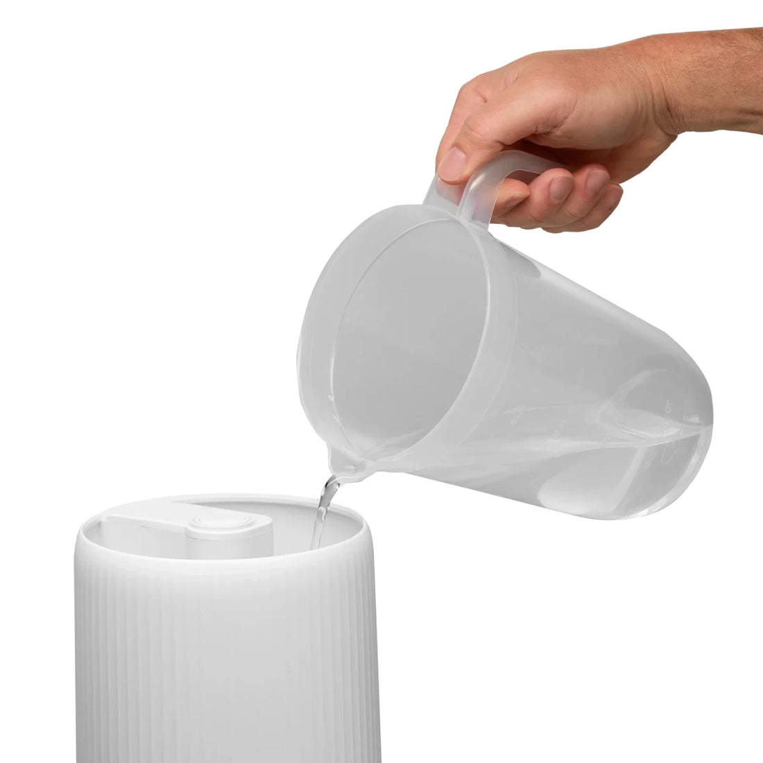 White pitcher being filled with water from a clear container on a white background - okotoks hc pharmacy