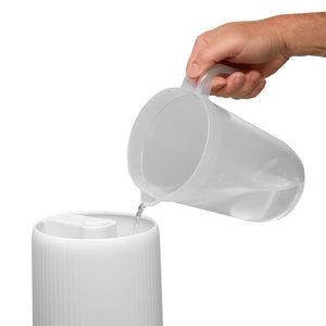 White pitcher being filled with water from a clear container on a white background - okotoks hc pharmacy
