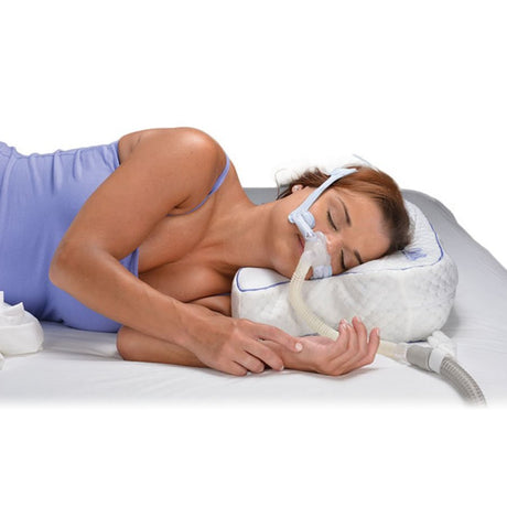 Woman using a CPAP machine with a pillow and mask on a white background - okotoks hc pharmacy