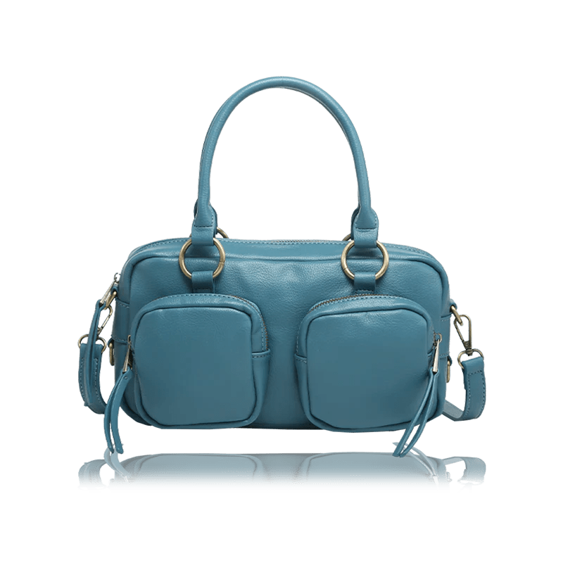 A teal blue leather handbag with dual top handles, two front zippered pockets, and gold-tone hardware, shown on a white background with a faint reflection below. - okotoks hc pharmacy