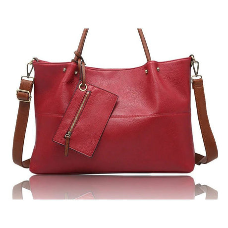 A red faux-leather handbag with brown leather handles, shoulder strap, and zipper pull, shown on a white background with a reflection below. - okotoks hc pharmacy