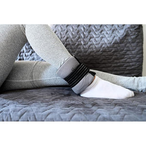 Person wearing a black ankle band on a gray textured surface - okotoks hc pharmacy