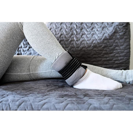 Person wearing a black ankle band on a gray textured surface - okotoks hc pharmacy