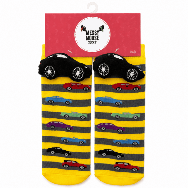 A pair of children's novelty socks in yellow and gray stripes with cartoon cars, shown hanging from a red 'Messy Moose Socks' retail hanger. The socks feature black car-shaped heels and toes with white wheels, and smaller multicolored cars printed along the sides. - okotoks hc pharmacy