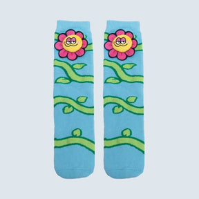 A pair of light blue crew socks featuring a cartoon floral pattern with pink flowers, yellow smiling faces, and green vines on a light gray background. - okotoks hc pharmacy