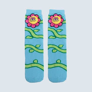 A pair of light blue crew socks featuring a cartoon floral pattern with pink flowers, yellow smiling faces, and green vines on a light gray background. - okotoks hc pharmacy