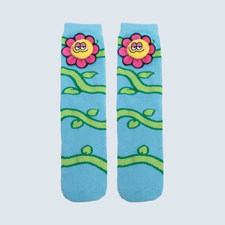A pair of light blue crew socks featuring a cartoon floral pattern with pink flowers, yellow smiling faces, and green vines on a light gray background. - okotoks hc pharmacy