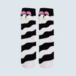 A pair of novelty socks featuring a black and white wavy zebra-like stripe pattern, with a cartoon face detail at the top showing pink eyebrows and white eyes, set against a solid light gray background. - okotoks hc pharmacy