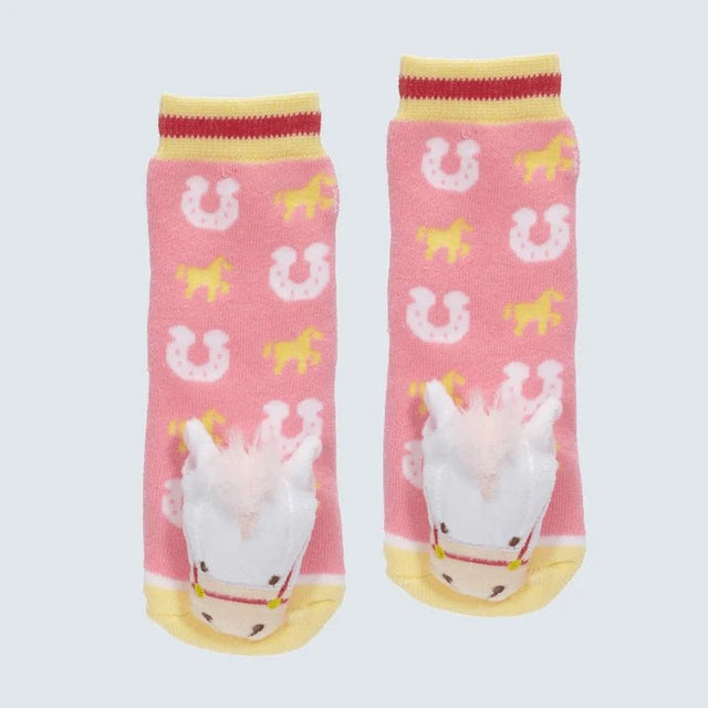 A pair of pink children's socks with a western theme, featuring yellow and white horseshoe and horse patterns, and a 3D white plush unicorn on the sole of each sock. - okotoks hc pharmacy
