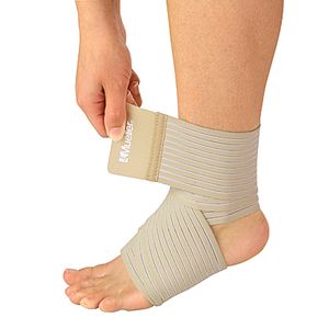 A beige ankle support brace being adjusted on a person's ankle by a hand, shown against a plain white background. - okotoks hc pharmacy