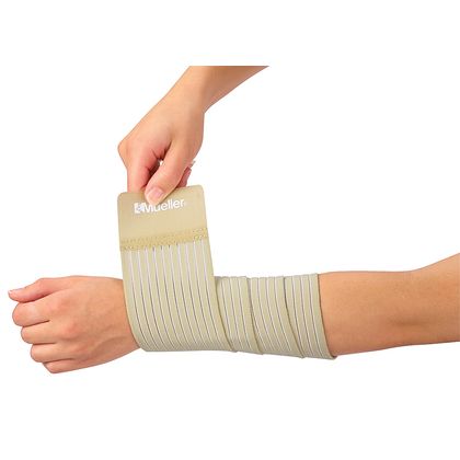 A person's arm and hand are shown wearing and adjusting a beige elastic compression sleeve with multiple pleated bands. The brand name 'Mueller' is printed on the top cuff. - okotoks hc pharmacy