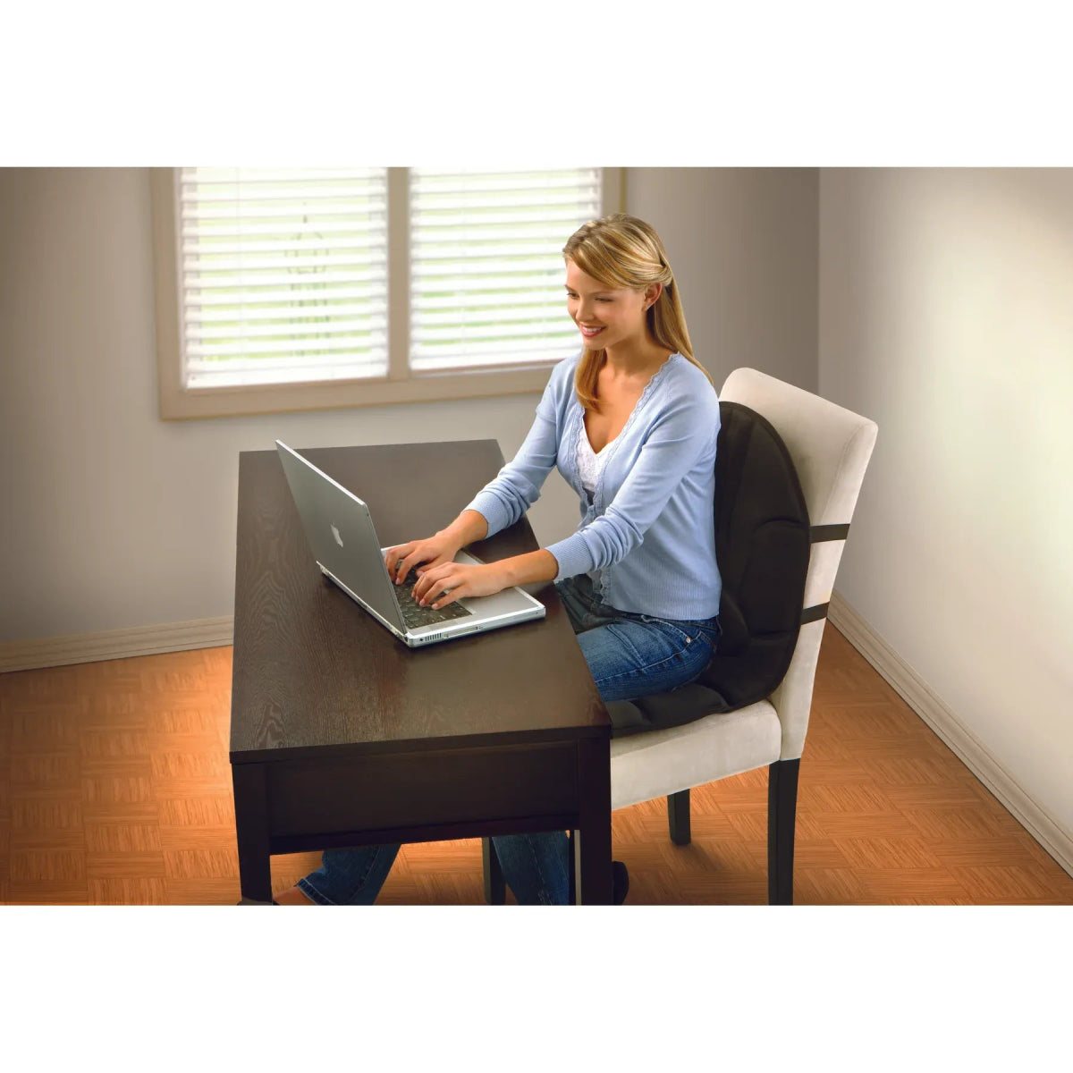 Woman using a laptop at a desk with a neutral background - okotoks hc pharmacy