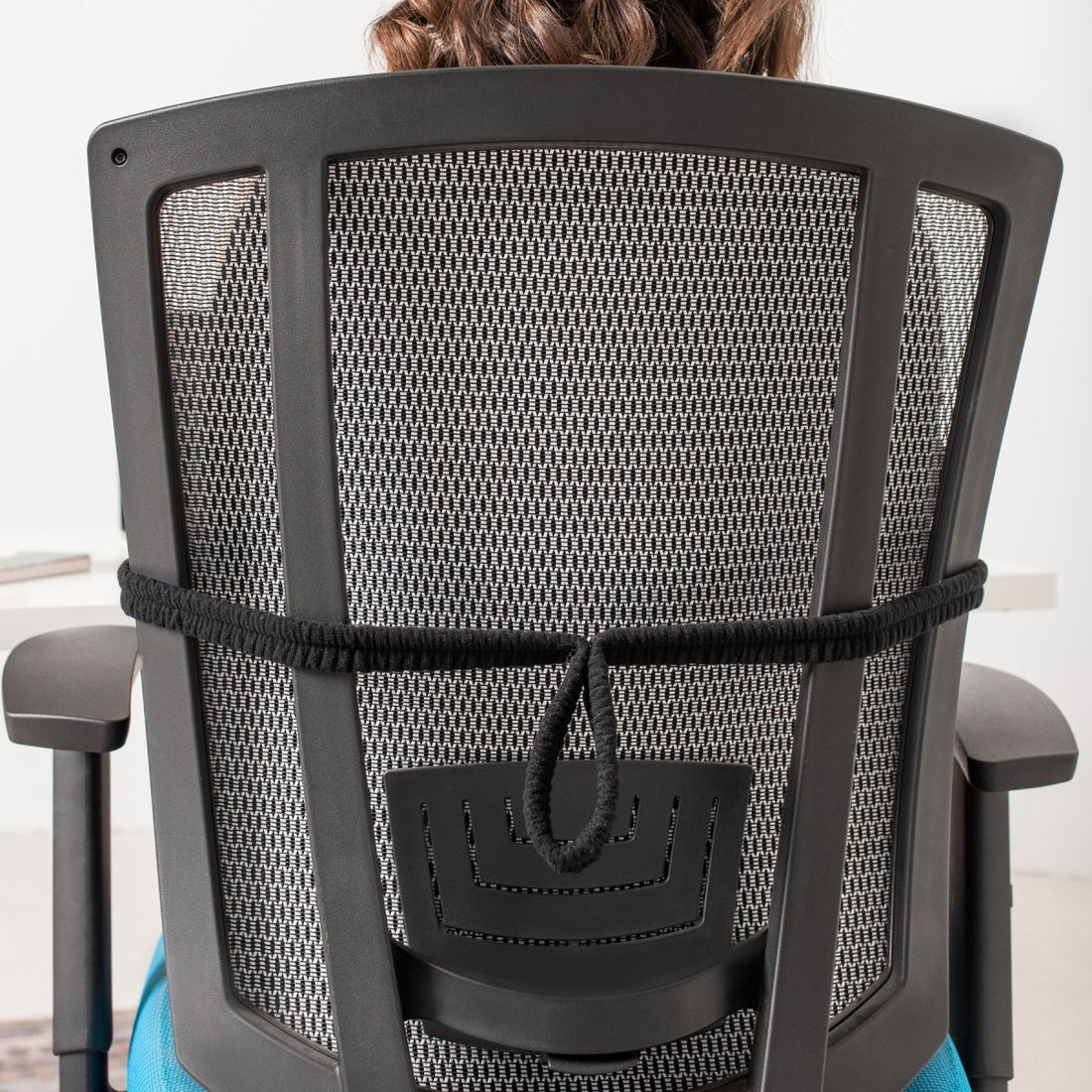 Person sitting on a black office chair with mesh backrest - okotoks hc pharmacy