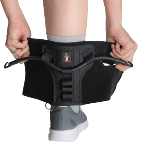 Person wearing a black athletic support brace on a white background - okotoks hc pharmacy