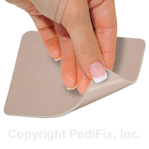 Hand applying a beige adhesive patch on a white background - okotoks hc pharmacy