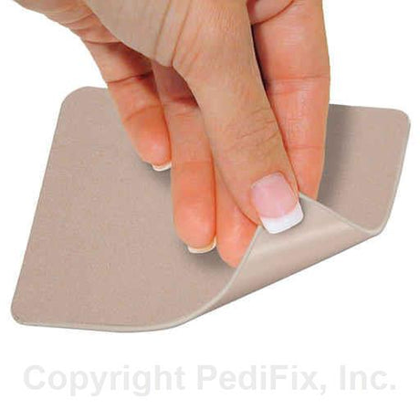 Hand applying a beige adhesive patch on a white background - okotoks hc pharmacy