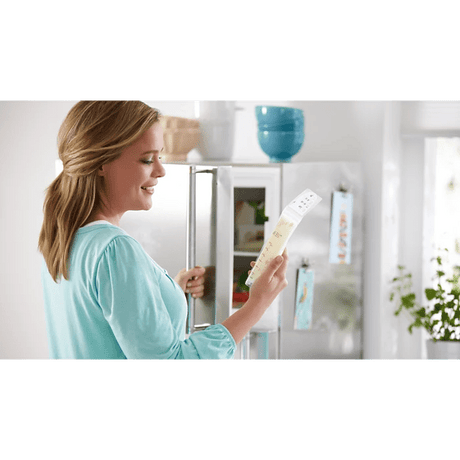 Woman holding a baby bottle in a kitchen setting - okotoks hc pharmacy
