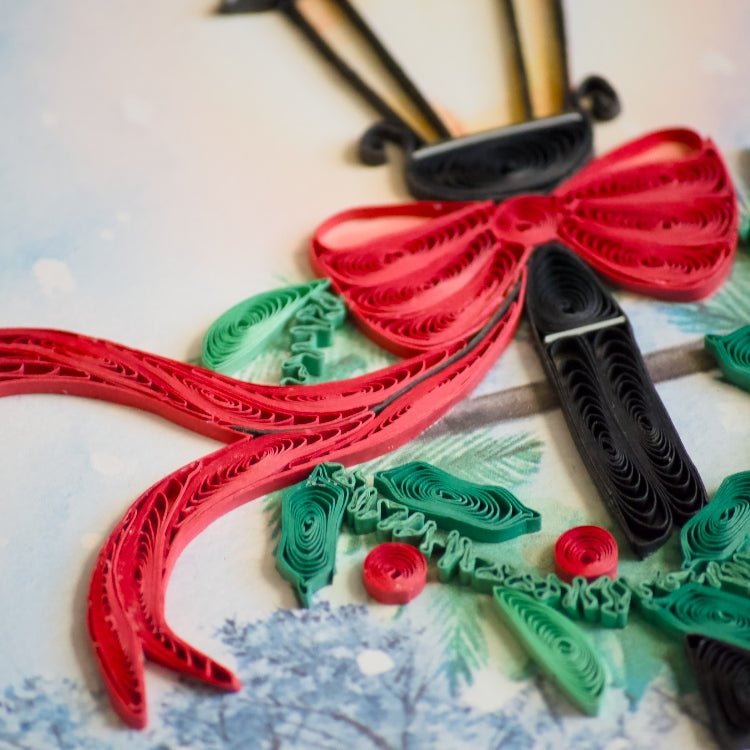 Quilled paper art of a Christmas wreath with red, green, and black ribbons on a textured white background. - okotoks hc pharmacy