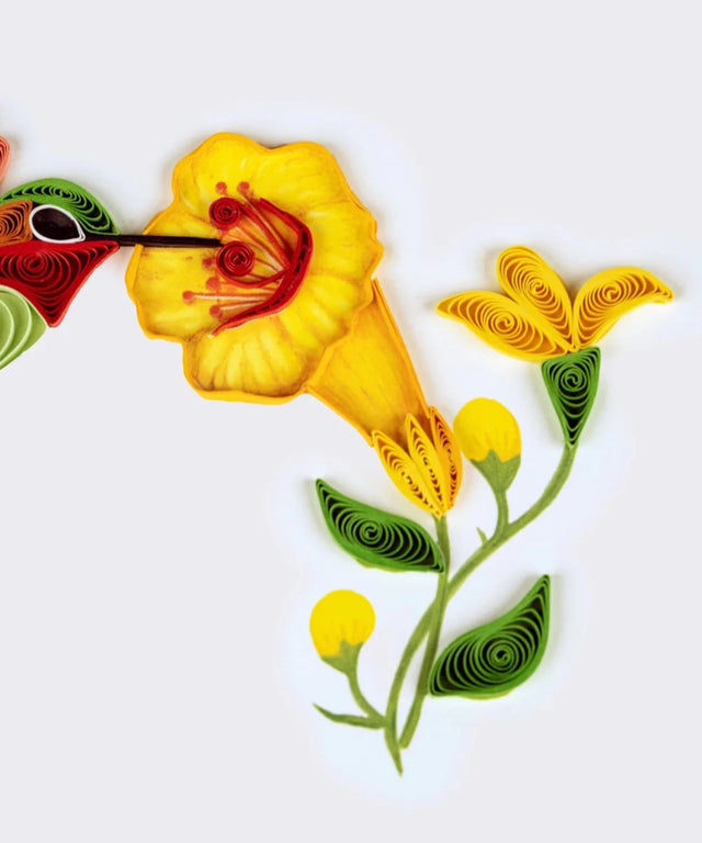 Quilled artwork of a hummingbird and flowers on a white background - okotoks hc pharmacy