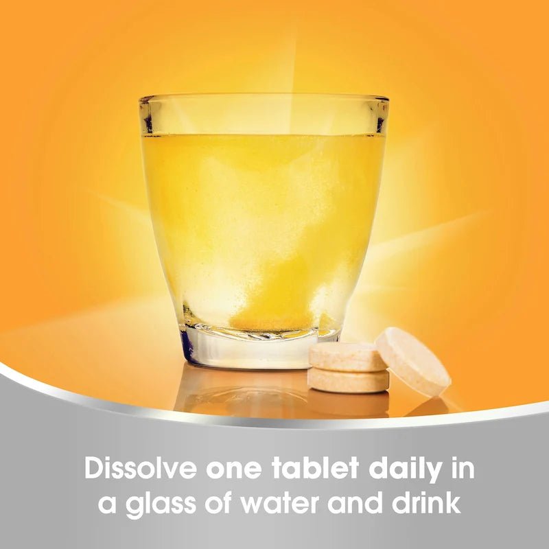 Glass of water with a tablet daily on an orange background - okotoks hc pharmacy