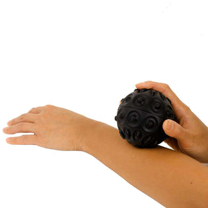 Person using a black massage ball on their arm against a white background - okotoks hc pharmacy