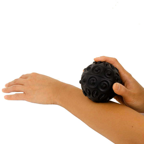 Person using a black massage ball on their arm against a white background - okotoks hc pharmacy