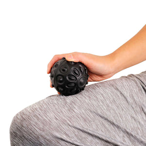 Hand holding a black textured ball against a white background - okotoks hc pharmacy