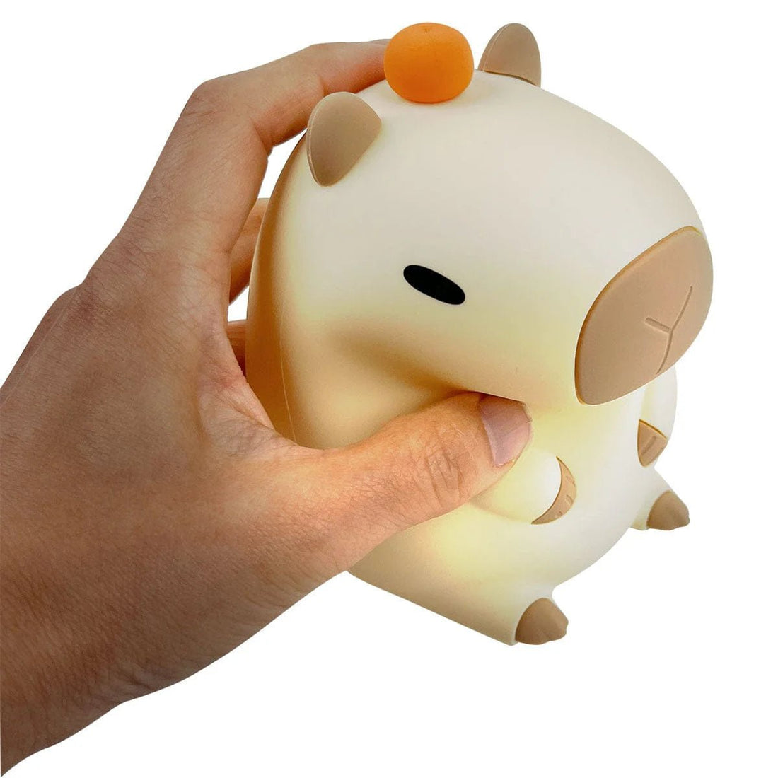 Hand holding a small, round, beige and brown night light shaped like a cartoon character on a white background. - okotoks hc pharmacy