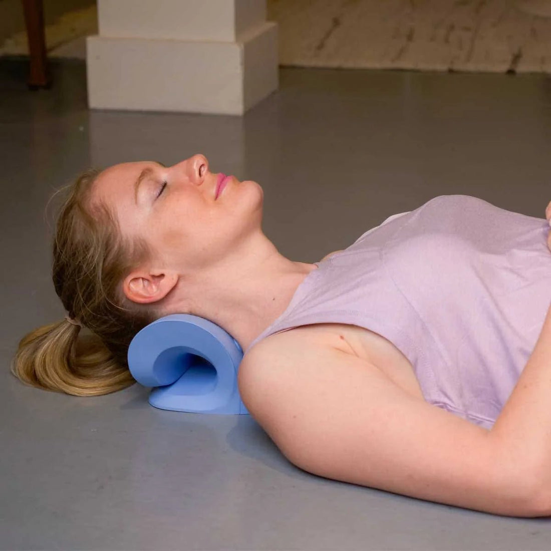 Woman lying on the floor with a blue neck pillow - okotoks hc pharmacy