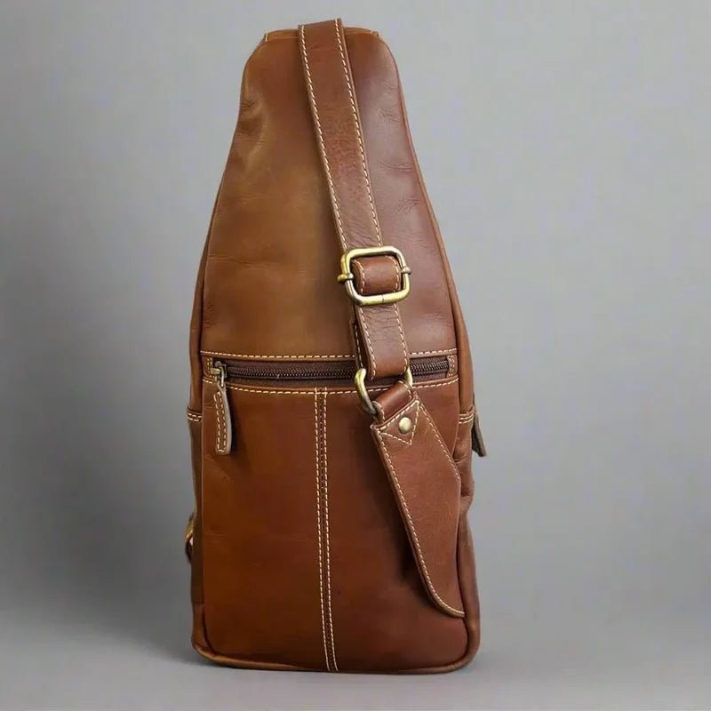 Brown leather sling bag with gold buckle on a gray background - okotoks hc pharmacy