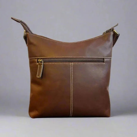 Brown leather handbag with a gold zipper on a gray background - okotoks hc pharmacy